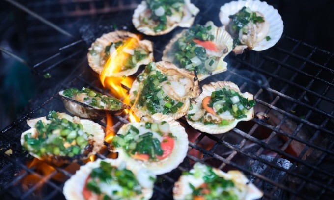 In addition to snails, these shops feature various seafood options, such as scallops prepared in different ways, like being grilled over charcoal. Photo by VnExpress/Quynh Tran